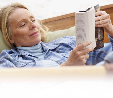 A woman relaxes in a boat while reading a book